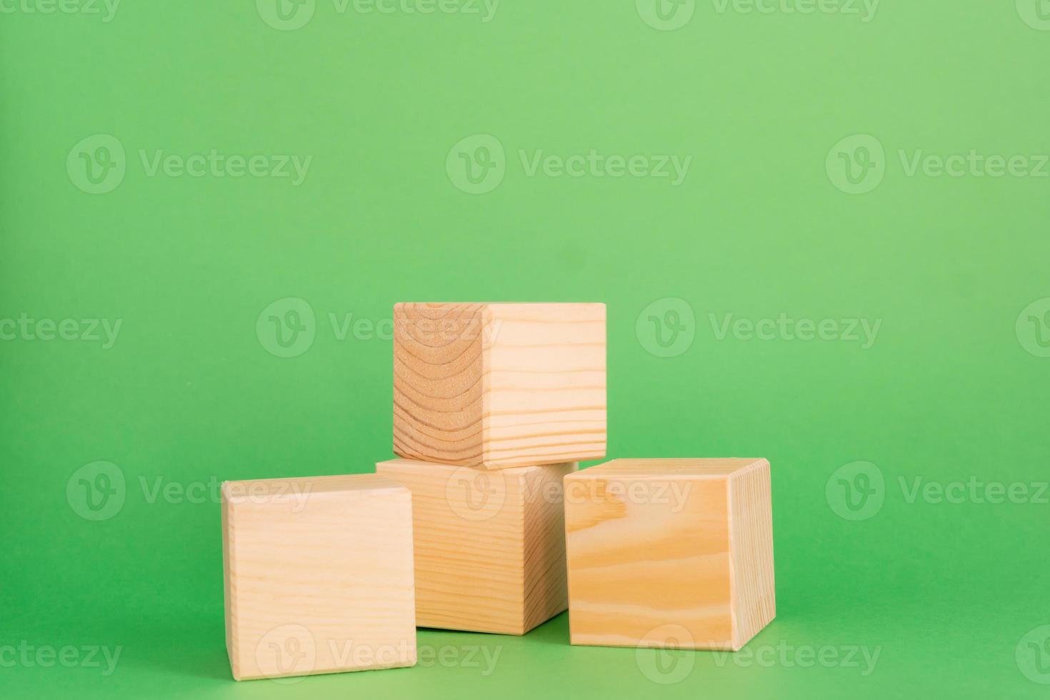 Construction of wooden cubes on green background with copy space. Mockup composition for design photo