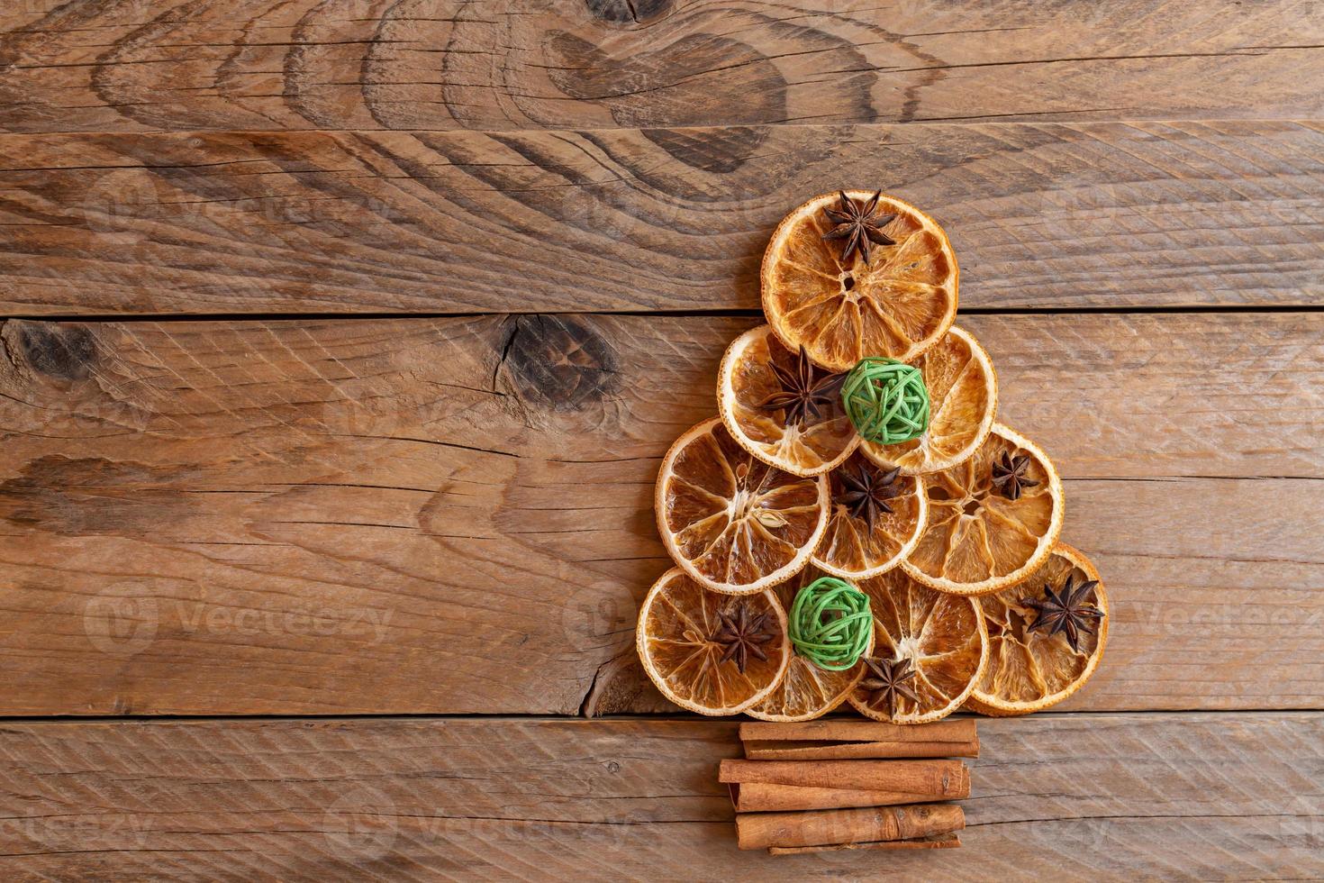 Christmas tree made of dried oranges, cinnamon and star anise on wooden background. copy space for text photo
