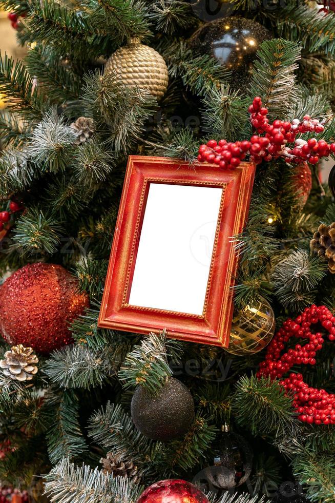 primer plano del árbol de navidad decorado con adornos de colores rojo, plateado y maqueta de marcos de fotos vacíos. concepto festivo de tarjeta de felicitación de invierno