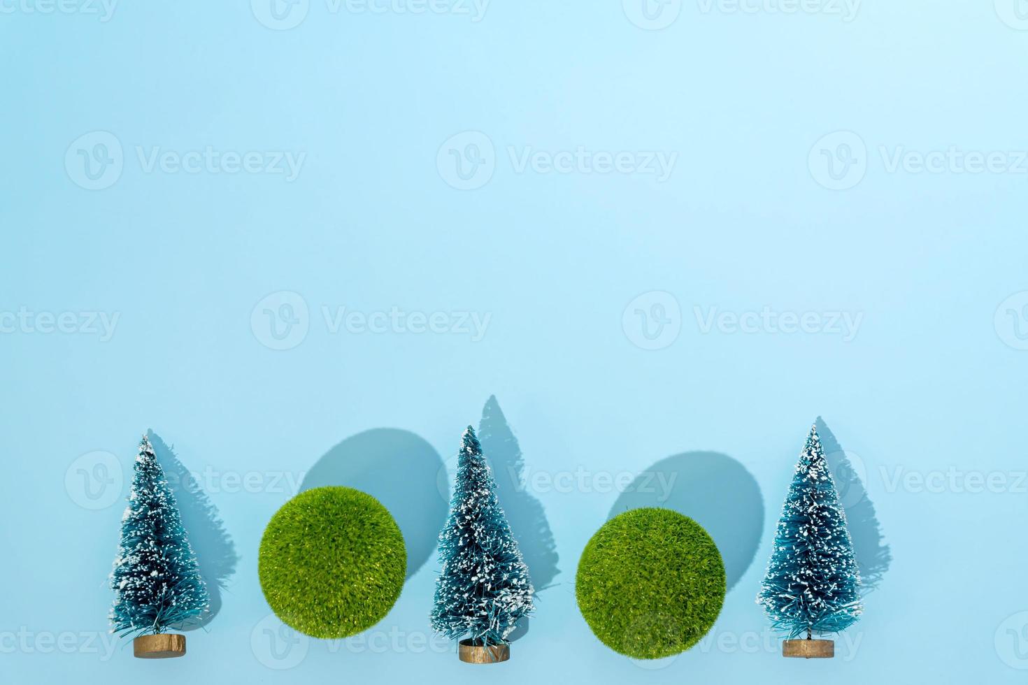 mini christmas trees and green balls on blue background with copy space for text or design. Christmas and New Year holiday concept. winter festive season. flat lay. photo