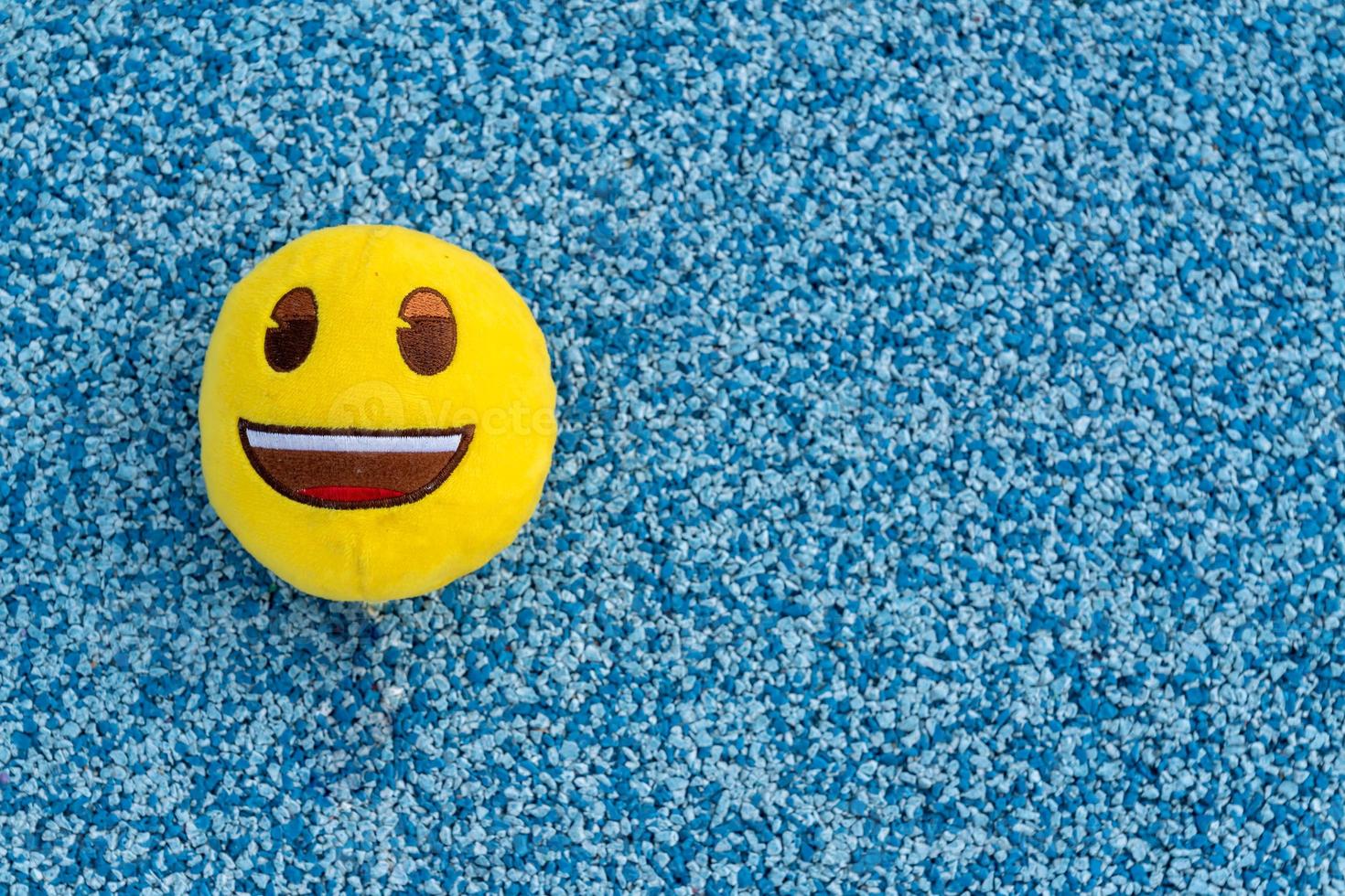 pelota amarilla textil de juguete con una sonrisa en el fondo verde foto
