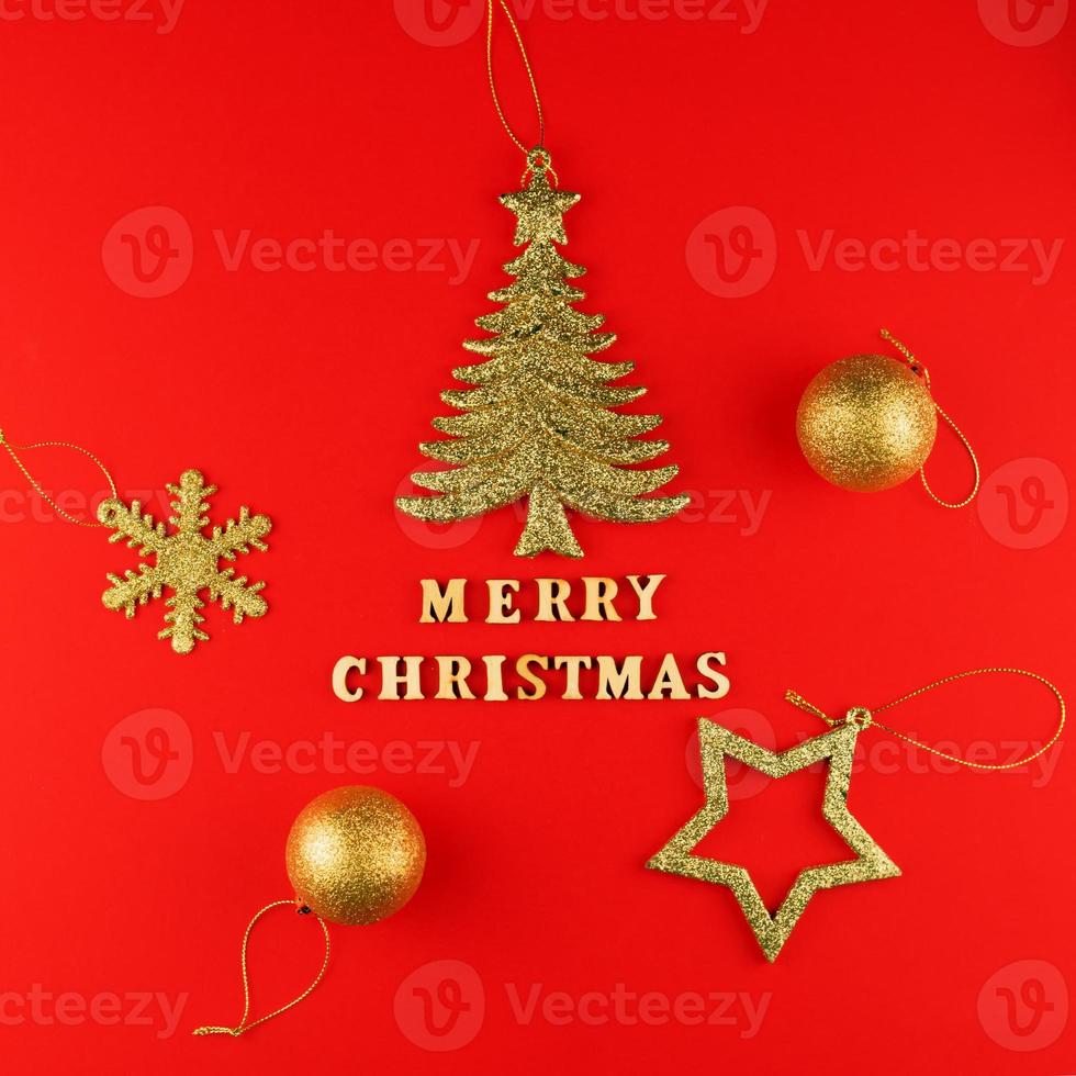 Festive greeting card. Merry christmas lettering on red paper with golden glittering toys. photo