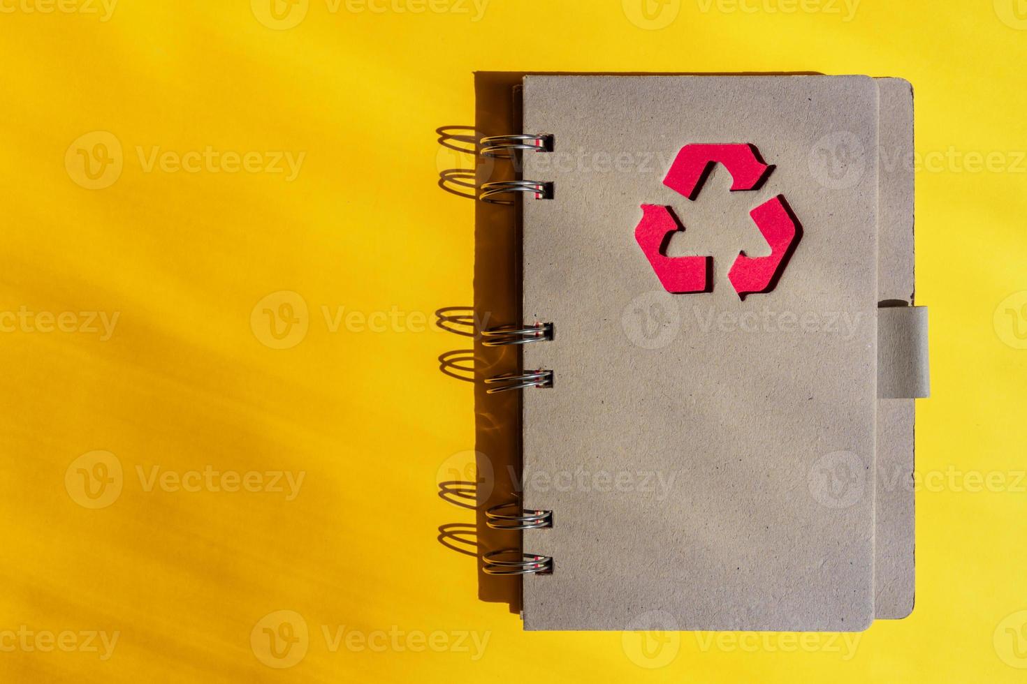 Planner of notebook with recycling sign on a cover on orange background. Consept of waste recycling. Top view, copy space. photo
