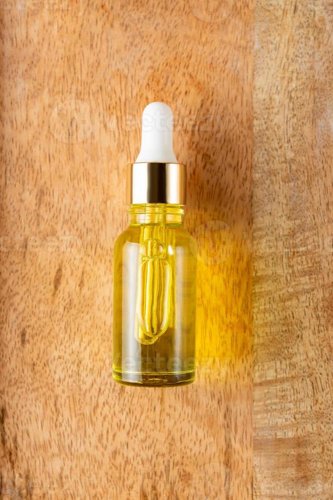 Skin care essence oil dropper glass bottle on wooden background. Hydrating serum, vitamin for face skin. Aesthetic, minimalism. photo