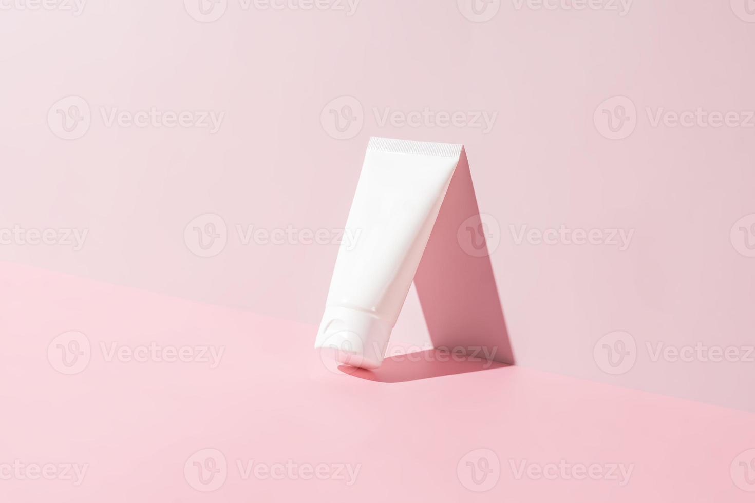 Cream tube on bright sunny pink background. Cosmetic skincare product blank plastic package. White unbranded lotion, balm, hand creme mockup. Sunscreen cream bottle photo