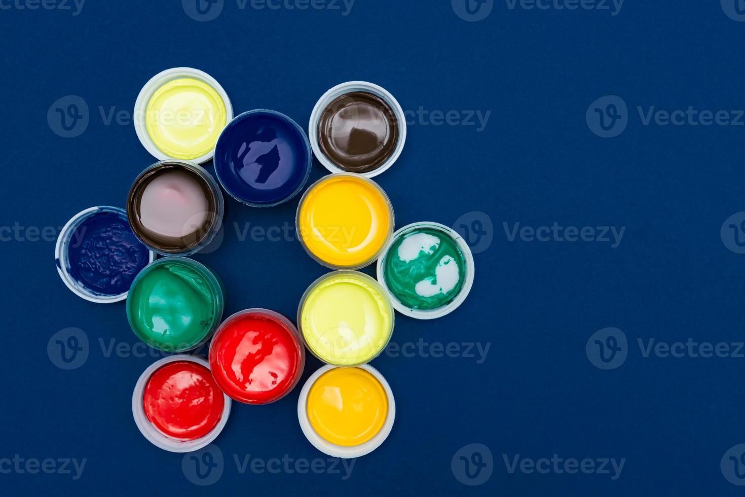 Top view of open acrylic paint cans. Colorful paints on blue background with copy space photo