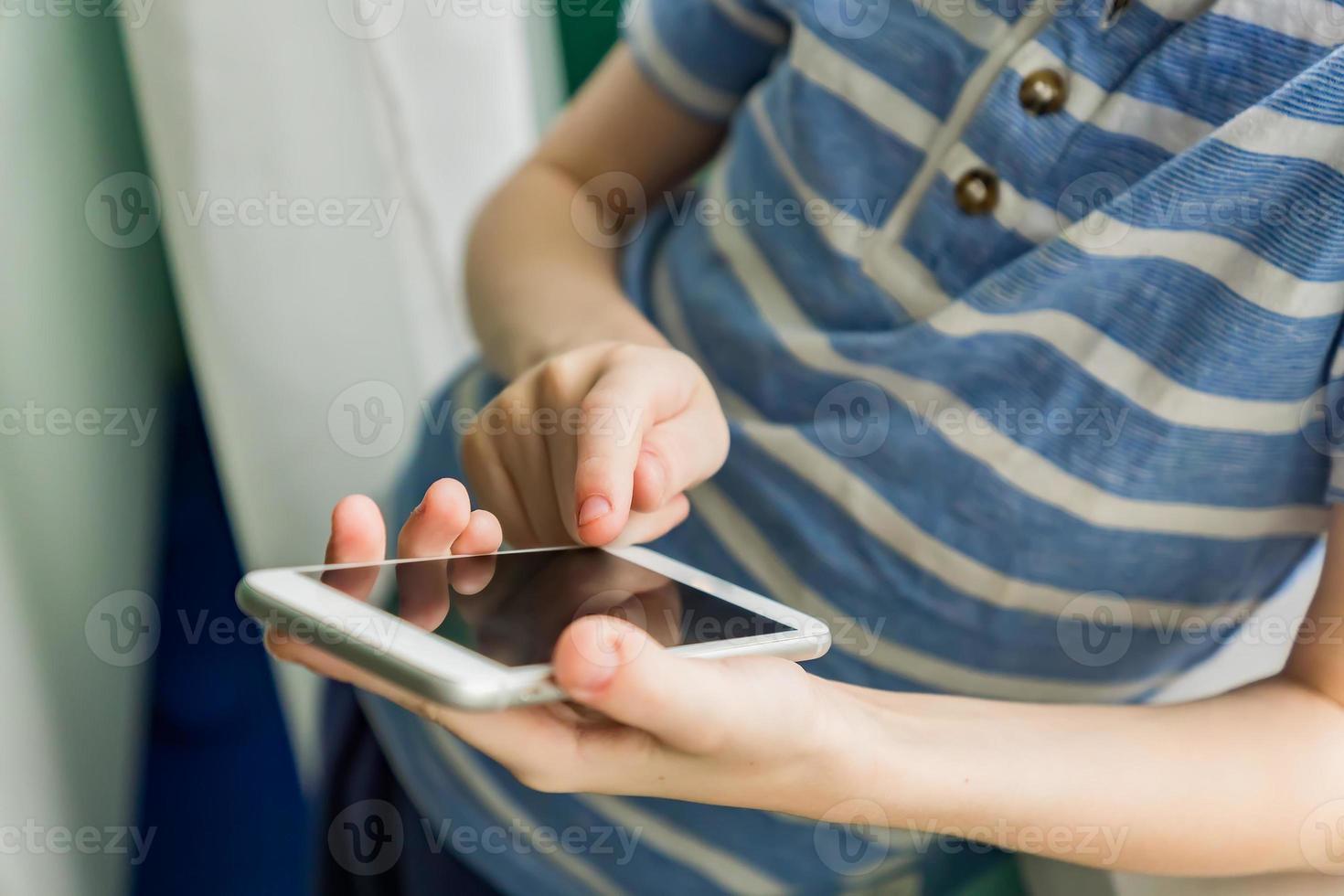 Close up of a kid hands using mobile smart phone. Selective focus photo