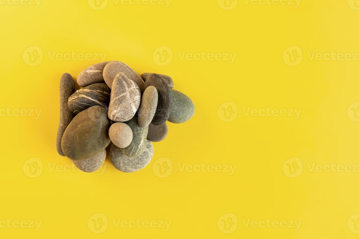 Flat lay in a trendy 2021 new colors. Illuminating Yellow and Ultimate Gray. Color of the Year 2021. Grey sea stones on yellow background. photo