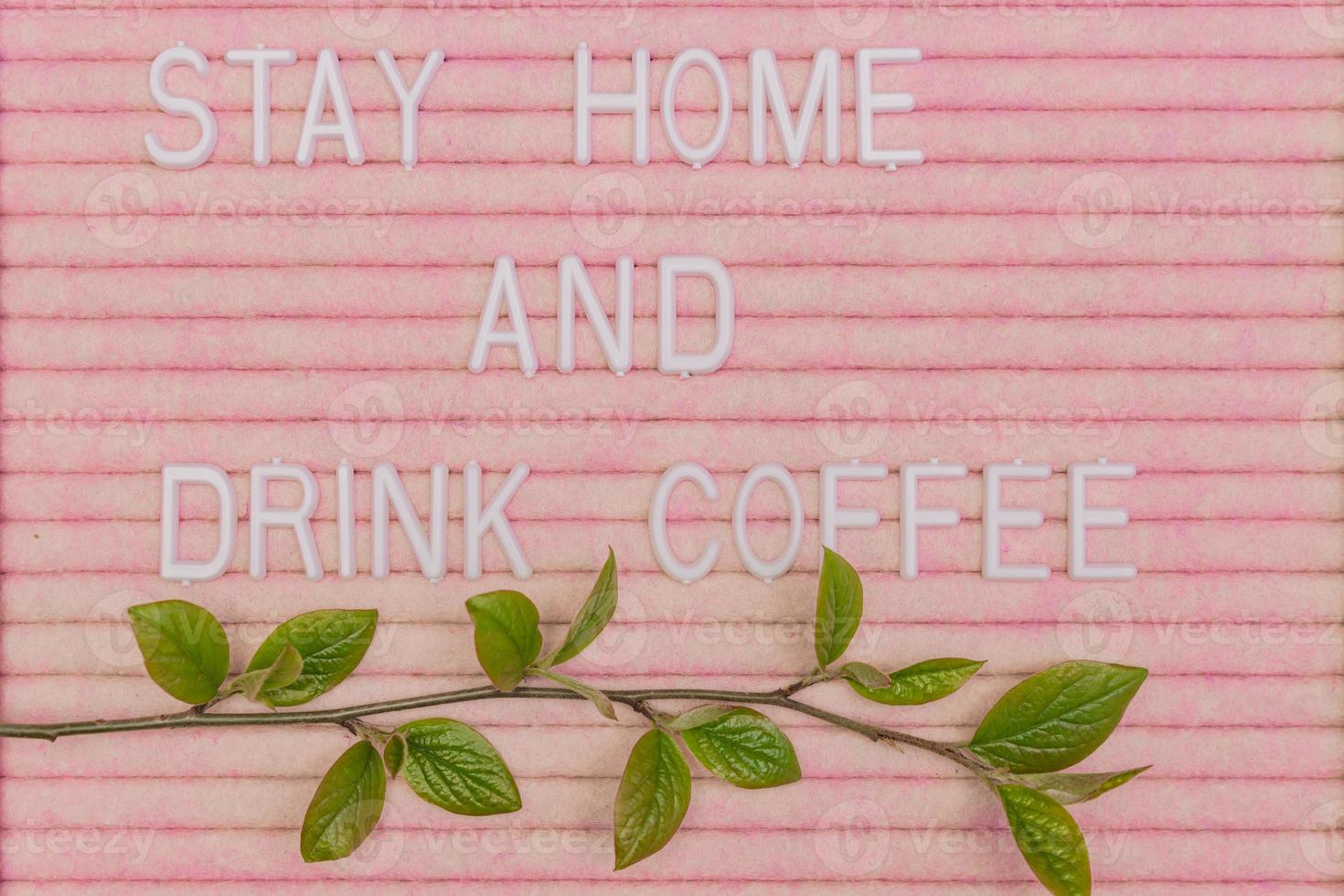 Lettreing booard with quote stay home and drink coffee decorated with spring branch with green fresh leaves. Spring motivation background. photo