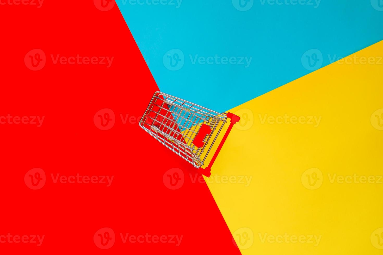 Top view of empty shopping trolley on colorful bright background. Concept of shopping and consumerism. Minimal flat lay. photo