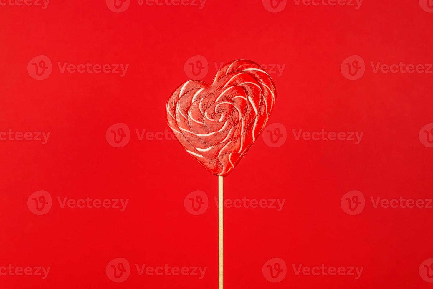 Single Valentines Day heart-shaped lollipop on red background. photo