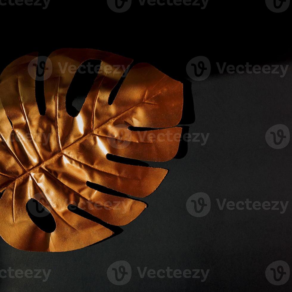 Fashionable luxuary black background with gold monstera leaf. Copy space for text photo
