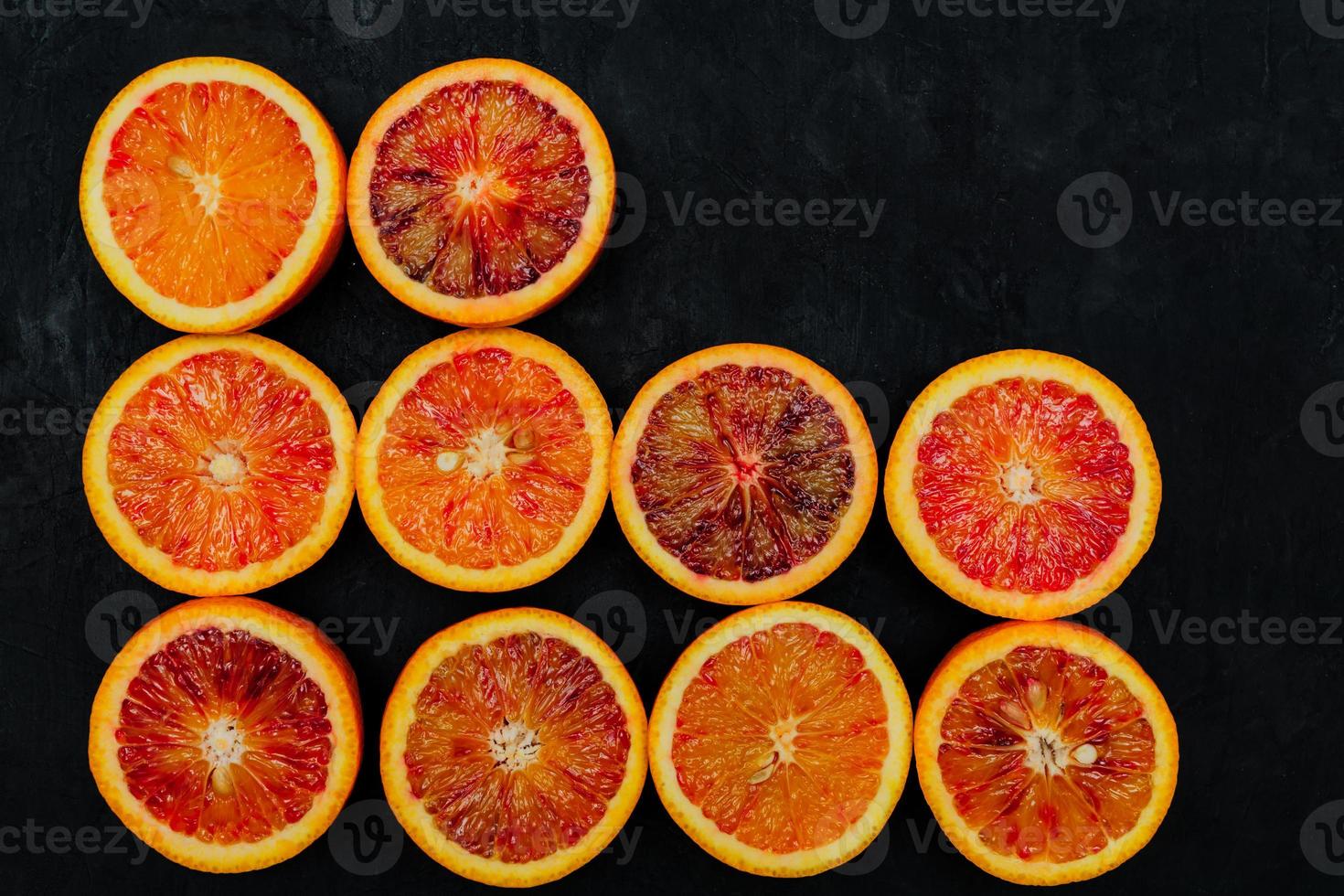 Beautiful background made of blood orange slices in a rows on black background. photo