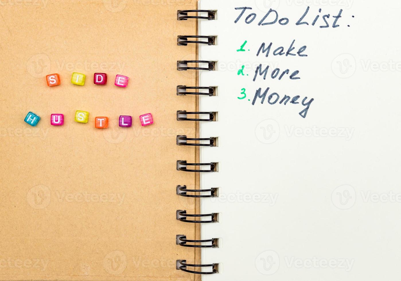 Side Hustle words made form multicolored square beads on spiral notebook cover. Concept image of passive income photo