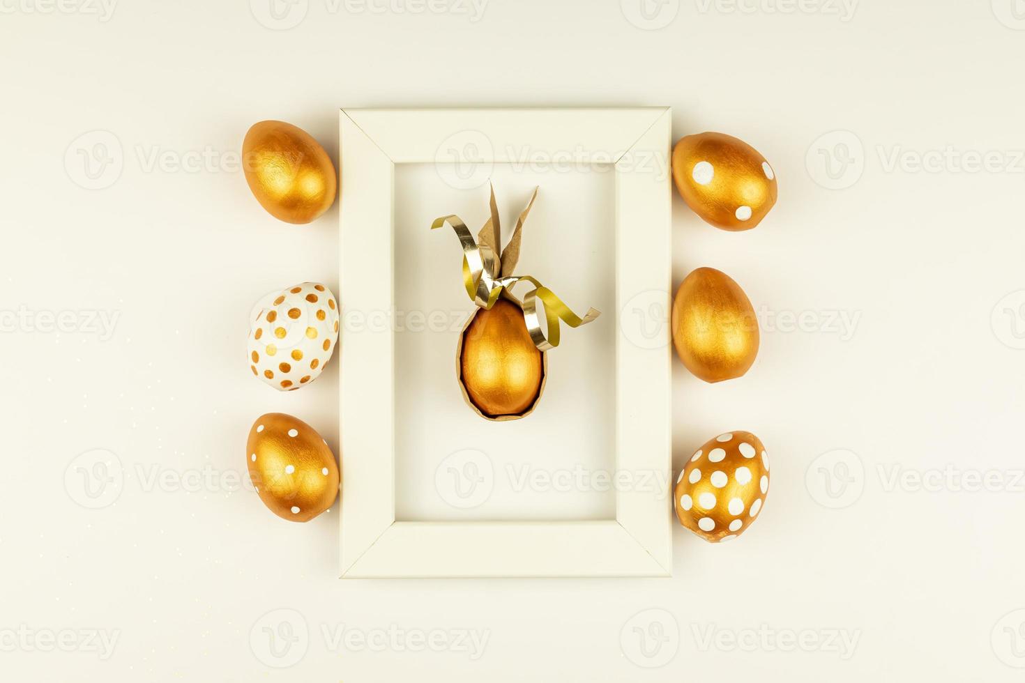 Easter festive decoration. Top view of easter eggs colored with golden paint and empty mock-up photo frame. Various dotted designs. White background.