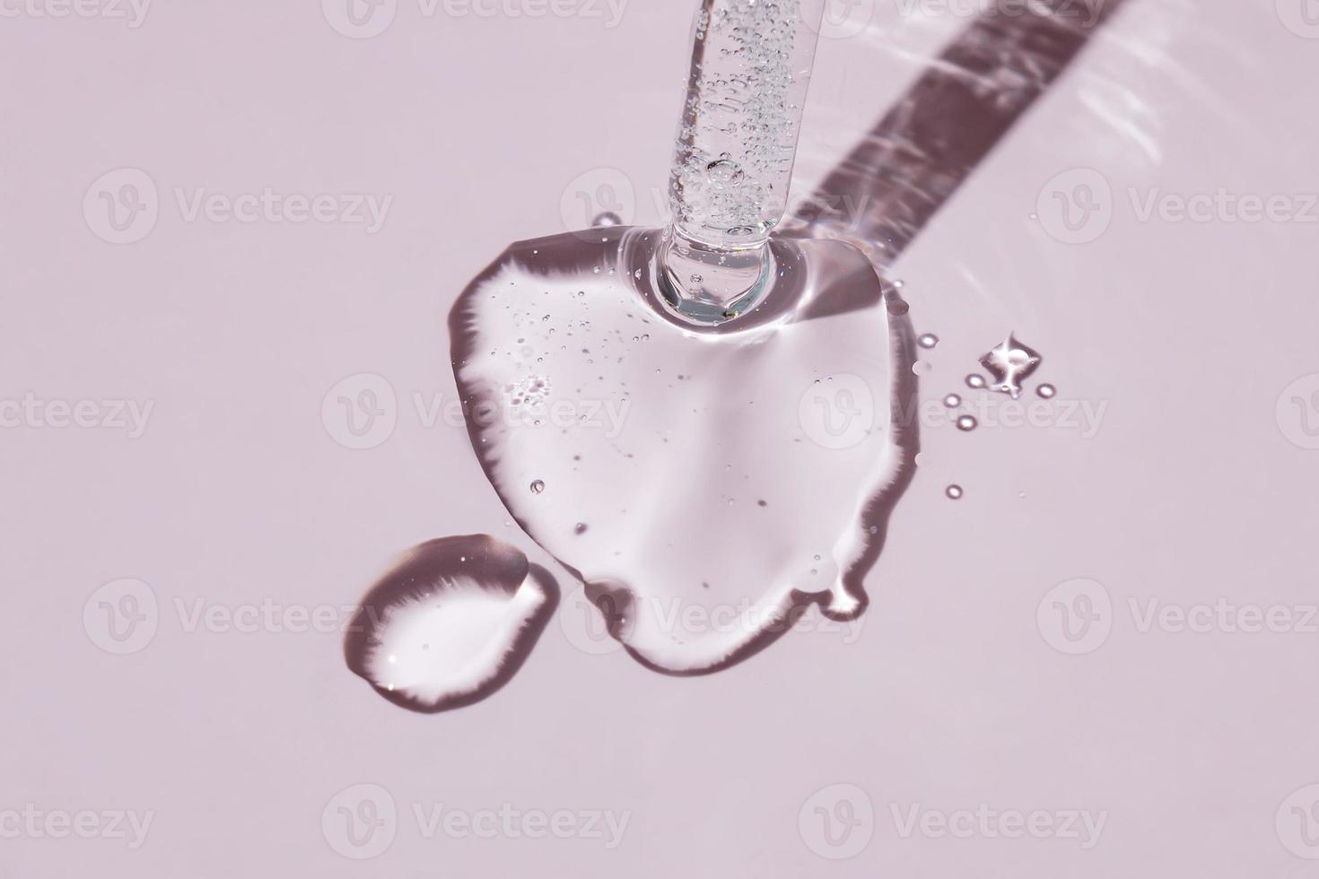 A cosmetic product gel or collagen serum flows out of a pipette with bubbles on pink background. photo