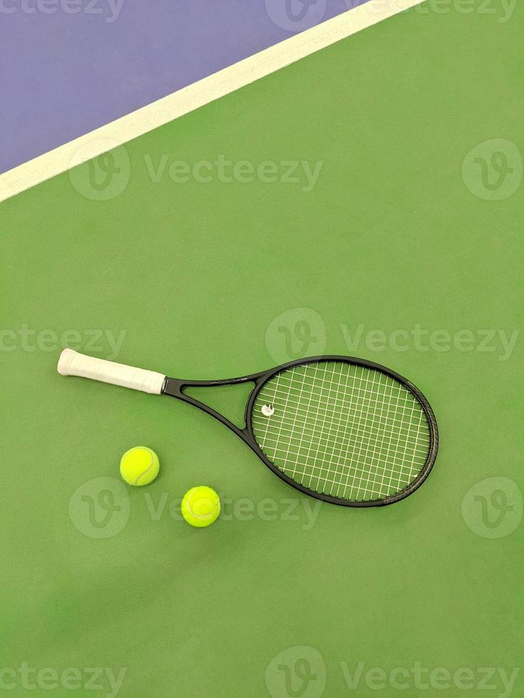 top view of tennis racket and two balls on the green clay tennis court photo