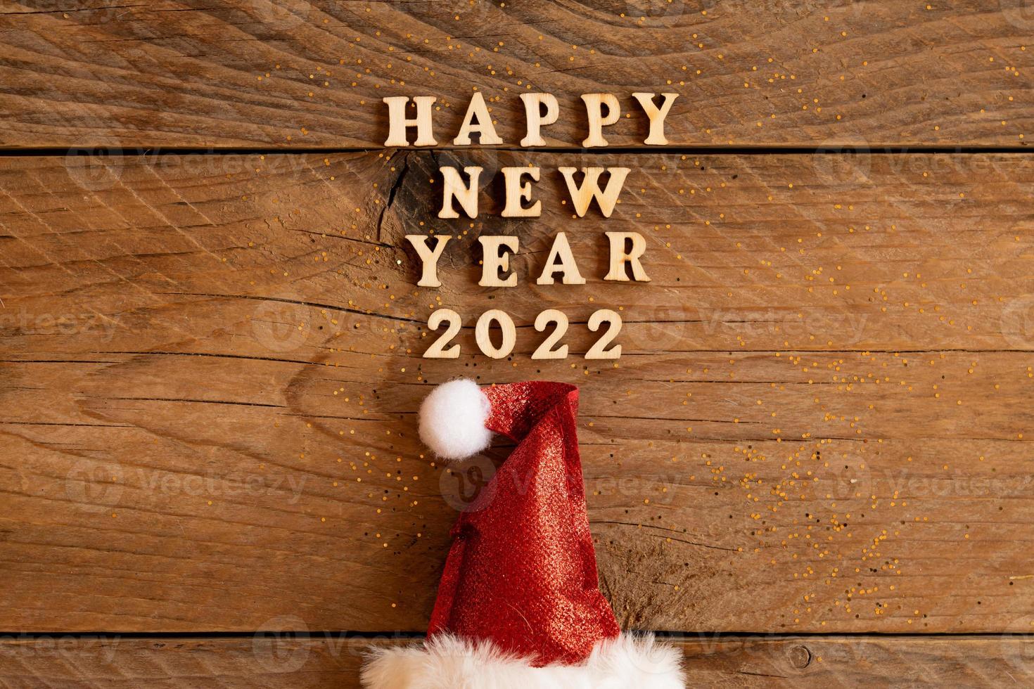 festive greeting card for 2022 new year with red santa hat and woodent text on a table. copy psace for text. photo