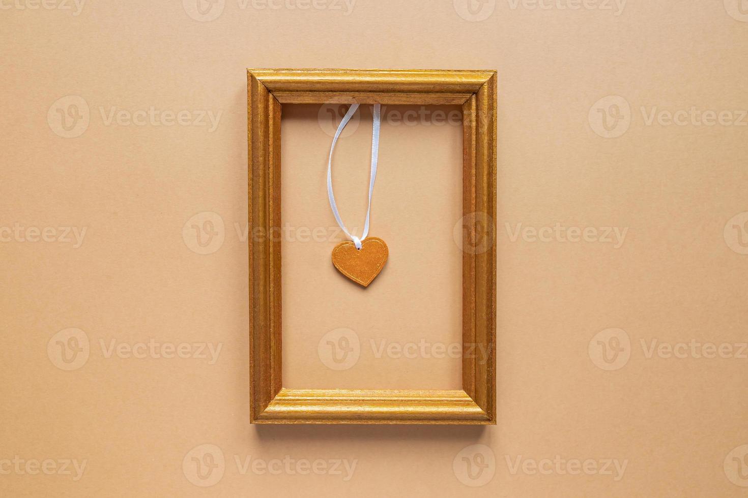 Valentine's day or Wedding romantic concept. golden photo frame with wooden heart inside on beige background.