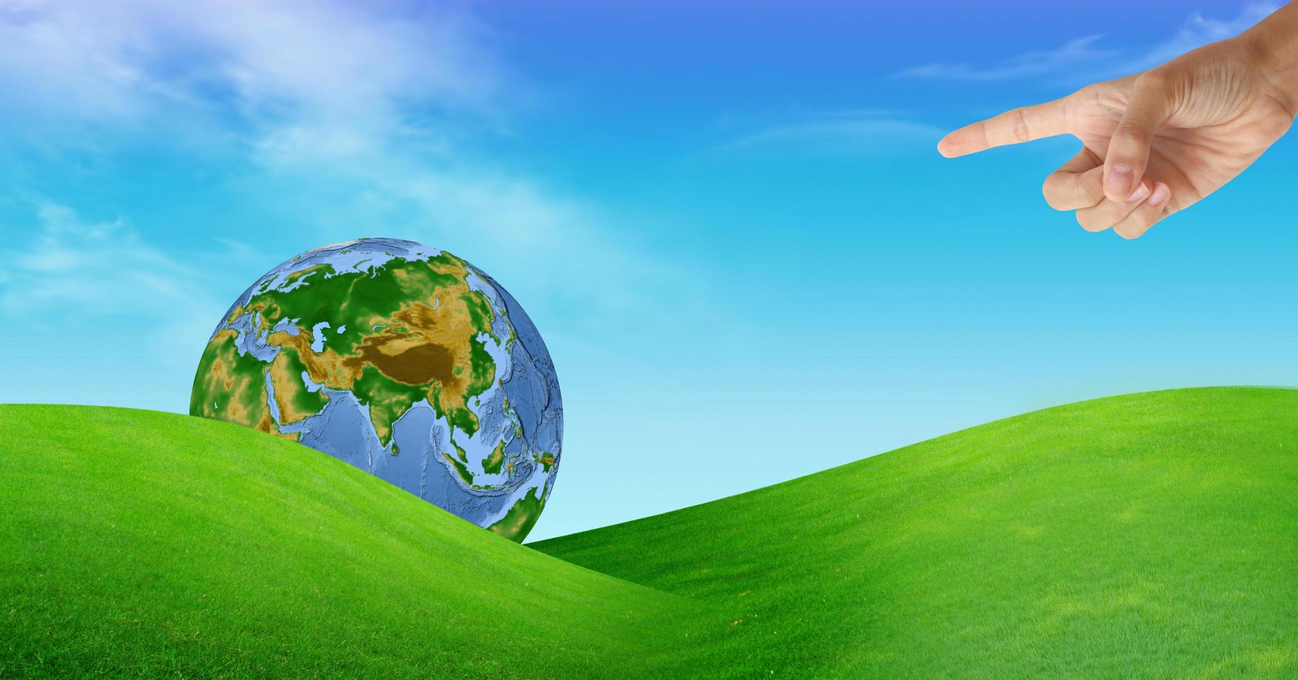 a hand with a globe and a grass field photo