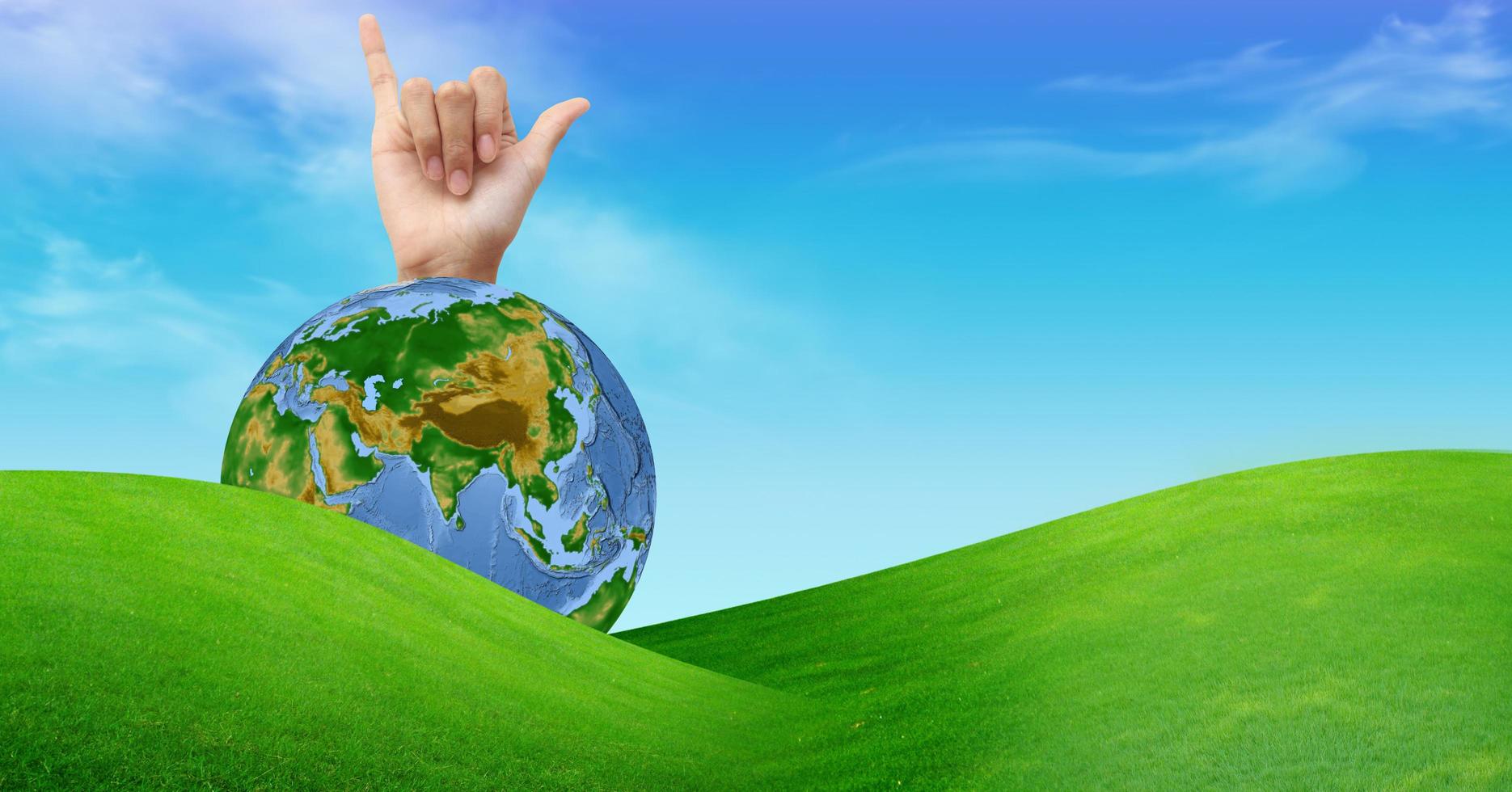 a hand with a globe and a grass field photo