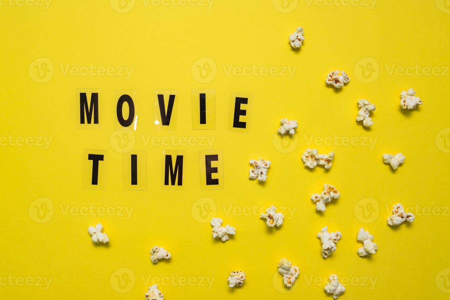 Movie Time text lettering with scattered salty popcorn on yellow background. photo