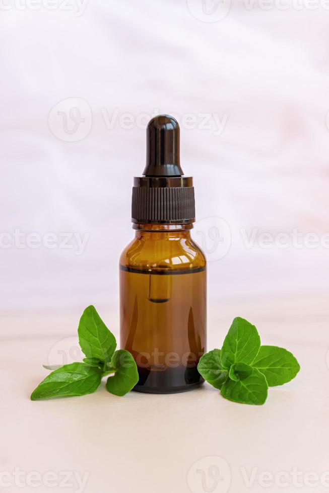 Mint essential oil in dark glass pipette bottle. Natural organic peppermint essence for aromatherapy and health treatment photo