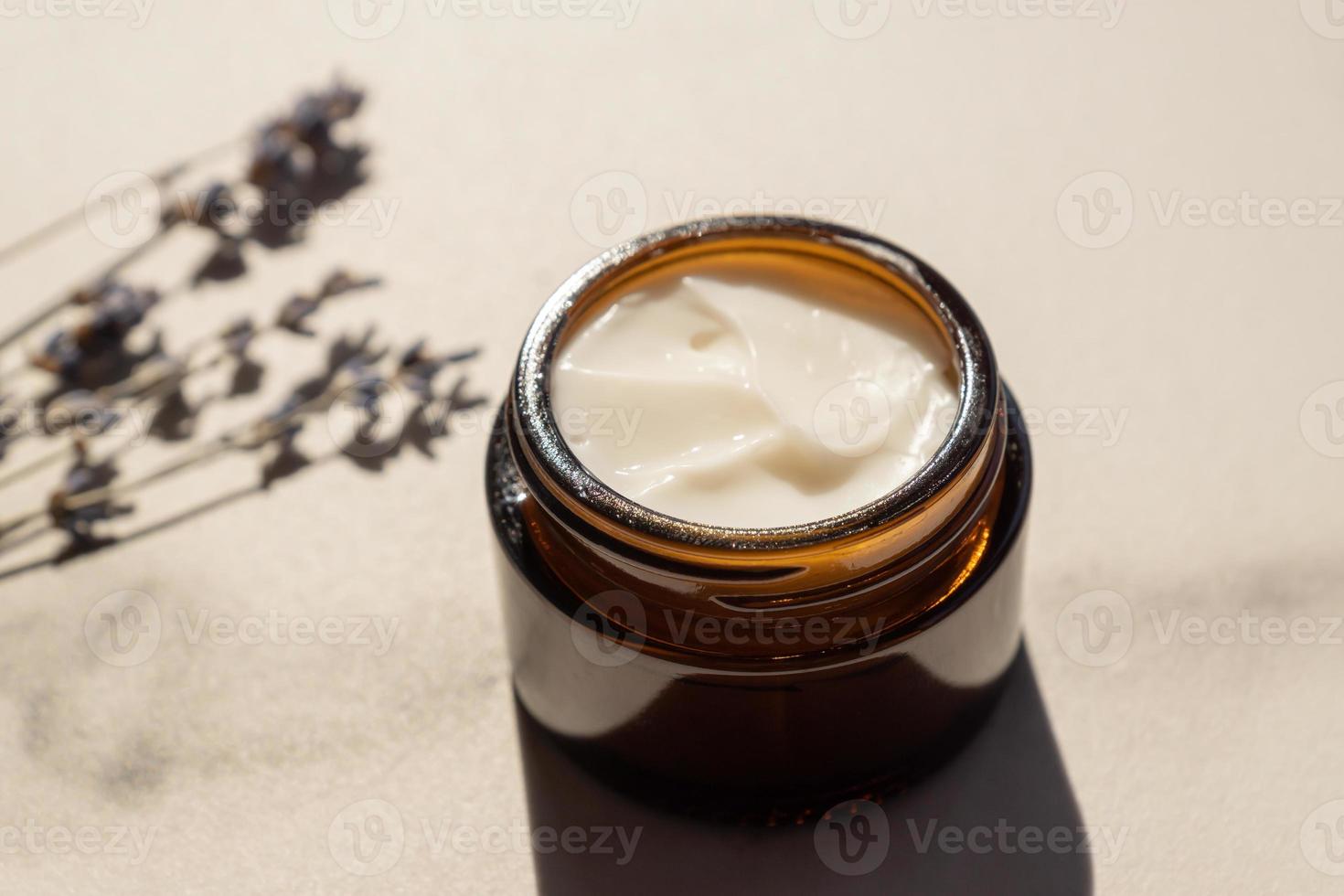 frasco de vidrio oscuro con crema de lavandula, flores de lavanda púrpura seca sobre mesa de mármol. aromaterapia herbal y cuidado de la piel. foto