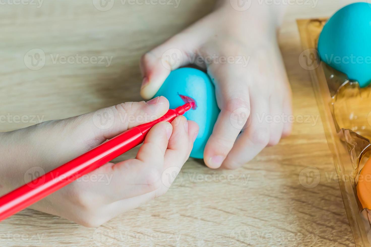 Child hand painting easter egg with felt-tip pen. Close up photo