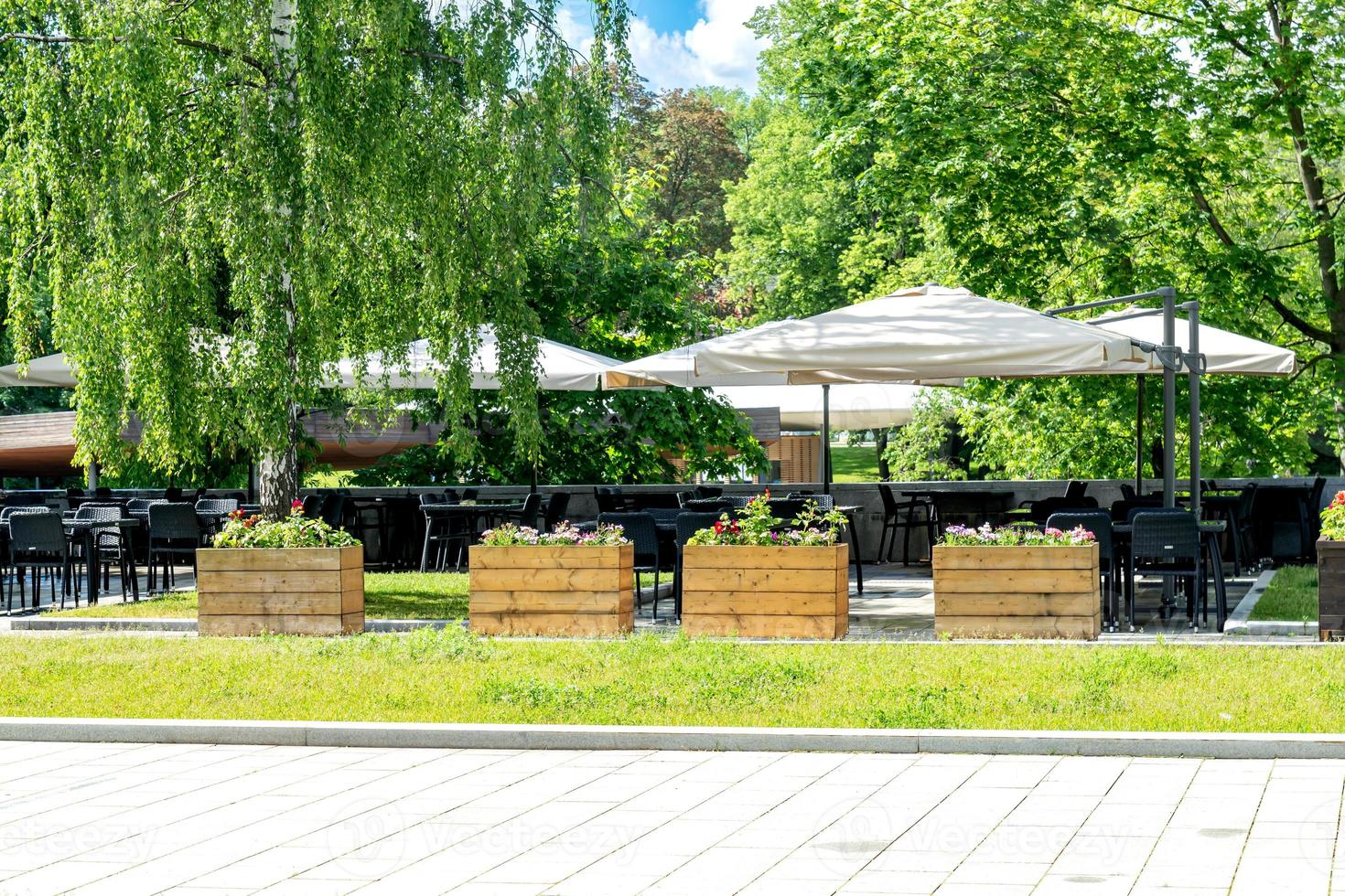 interior de café callejero de verano en el parque de la ciudad verde, adornado con flores y elementos decorativos a la sombra de los árboles foto