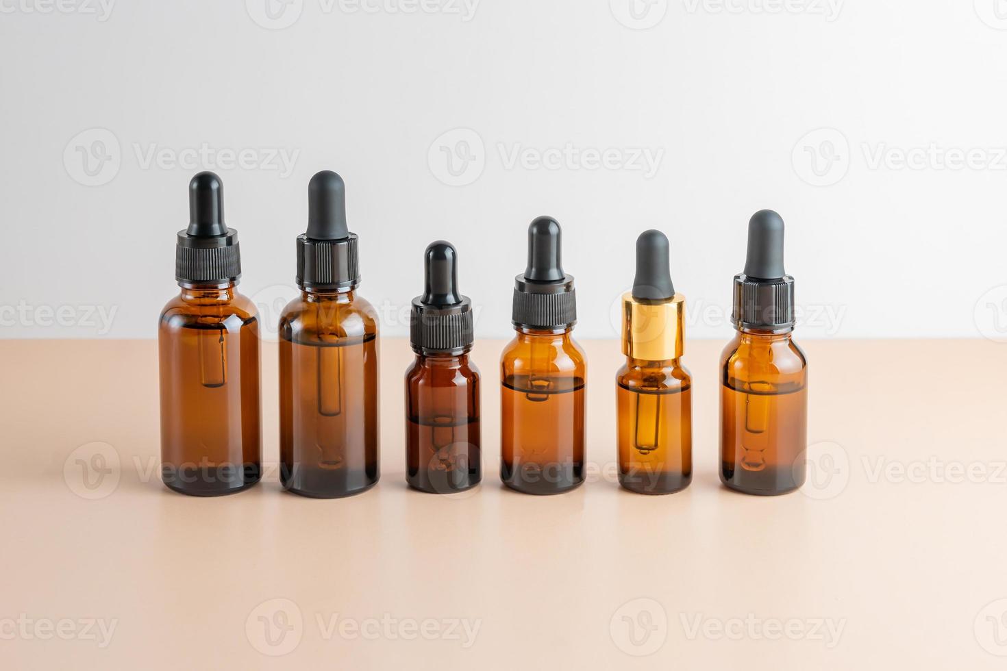 Set of famous dropper bottles with essential oils of beauty face serum with collagen, peptides, vitamins and extracts on a beige background. photo