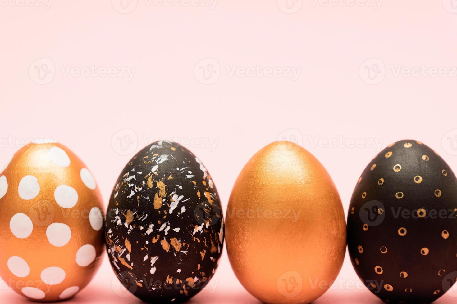 Side view of pink, white, black and golden decorated easter eggs in a row on pink background. Trendy holiday backdrop. photo