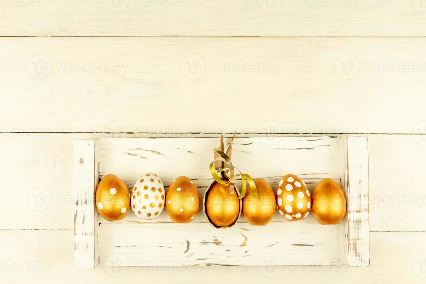 Easter festive decoration. Top view of easter eggs colored with golden paint and empty mock-up photo frame. Various dotted designs. White background.