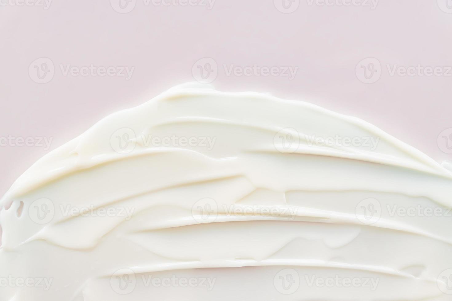 Texture of white cream on pink background. Smear of moisturizer close up. Lotion swatch. Beauty skin care product smear smudge. SPF sunscreen cream sample on pink background photo
