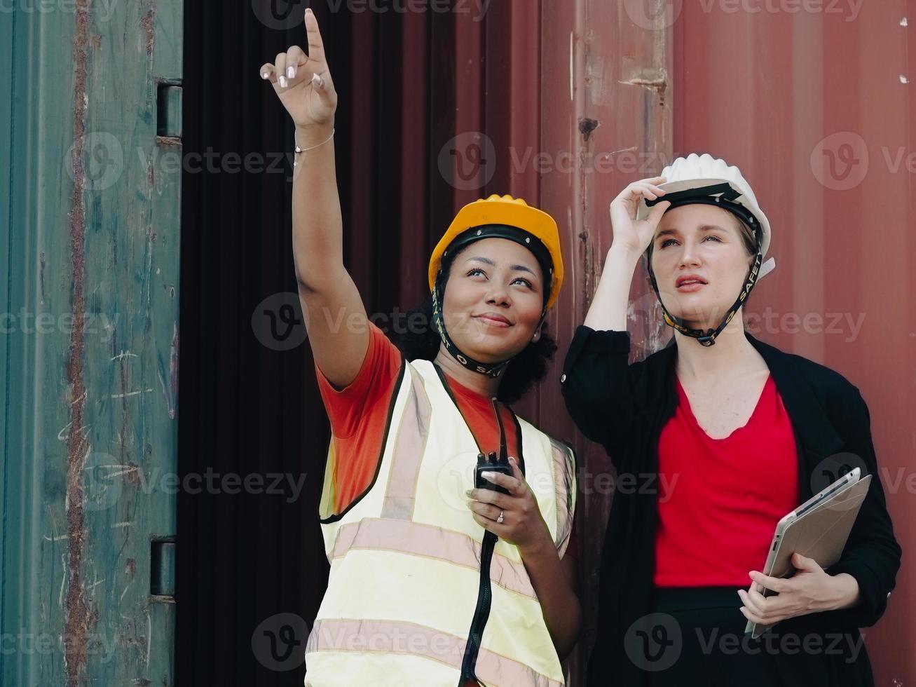 Diverse group of people working together at container terminal. Female African American foreman and industrial engineer woman manager standing at container depot. Diversity business people concept. photo