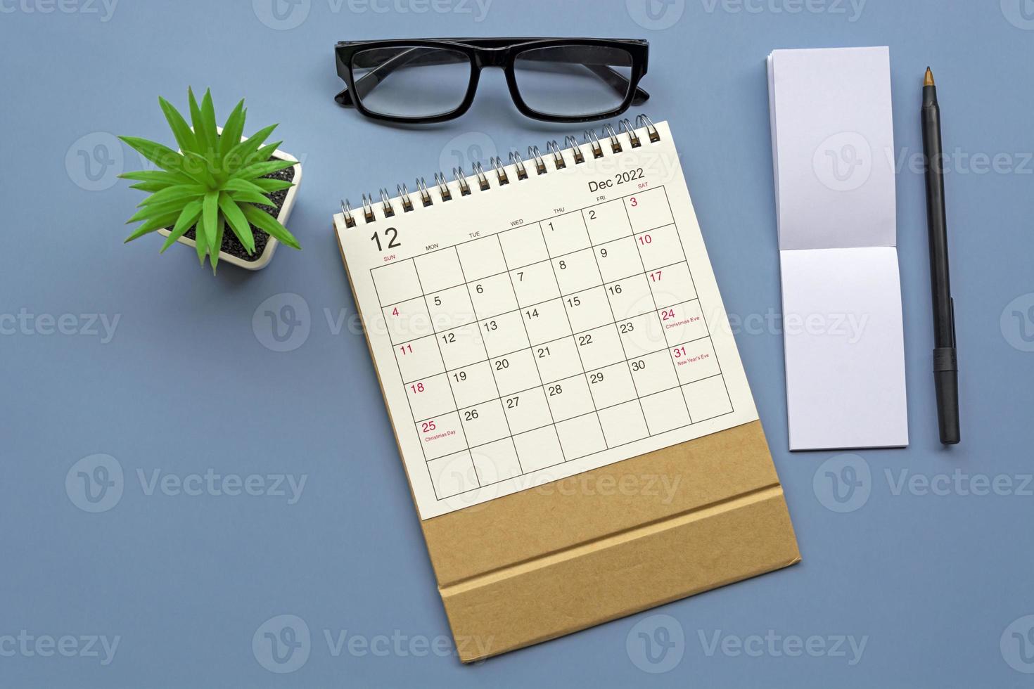 December 2022 desk calendar with notepad on blue background. Copy space. photo