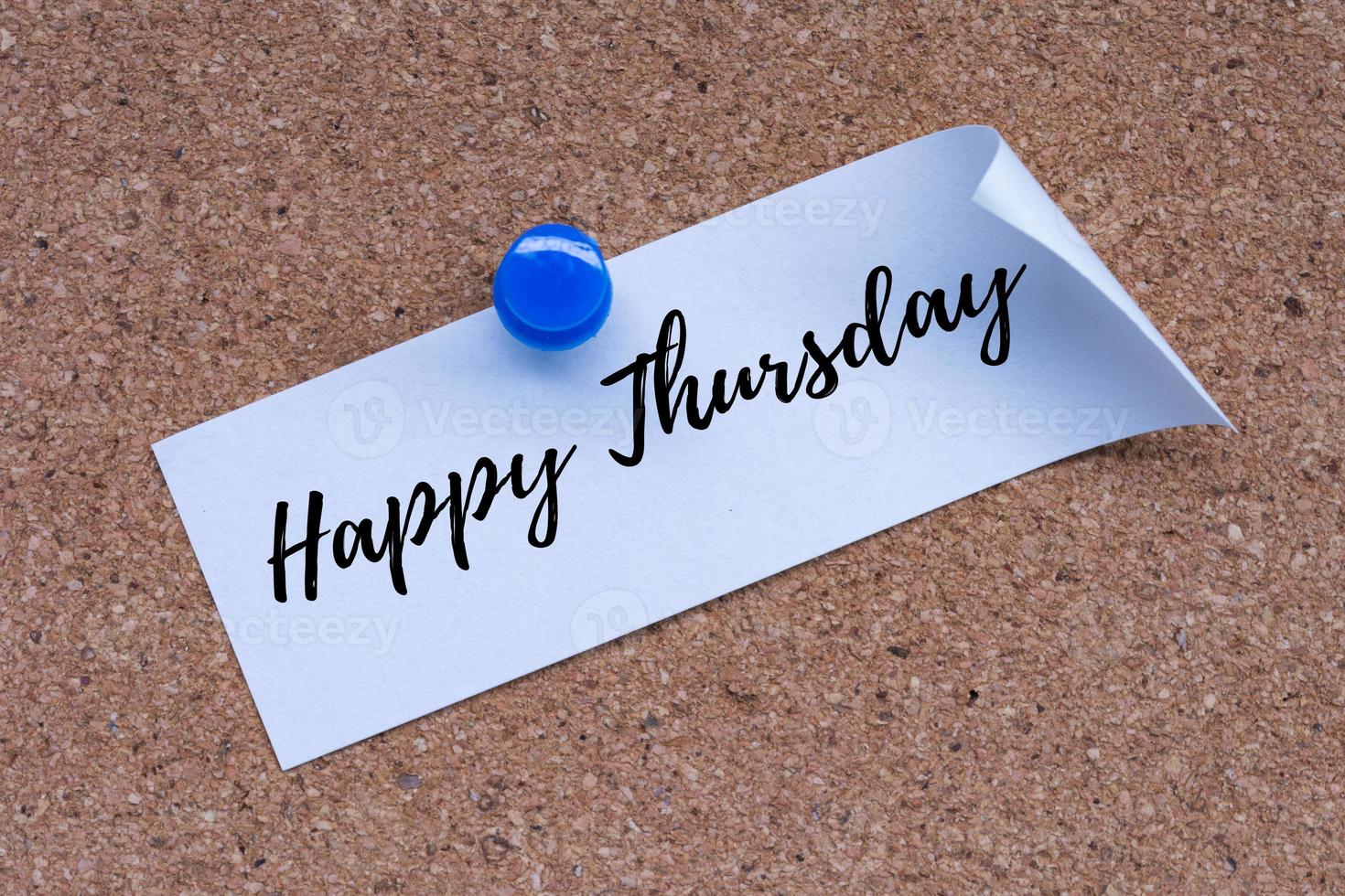 Happy Thursday text on white stick note and pinned to a cork notice board. photo