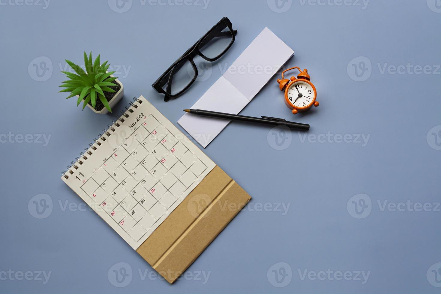 November 2022 desk calendar with alarm clock set at 9 o'clock. Copy space. photo