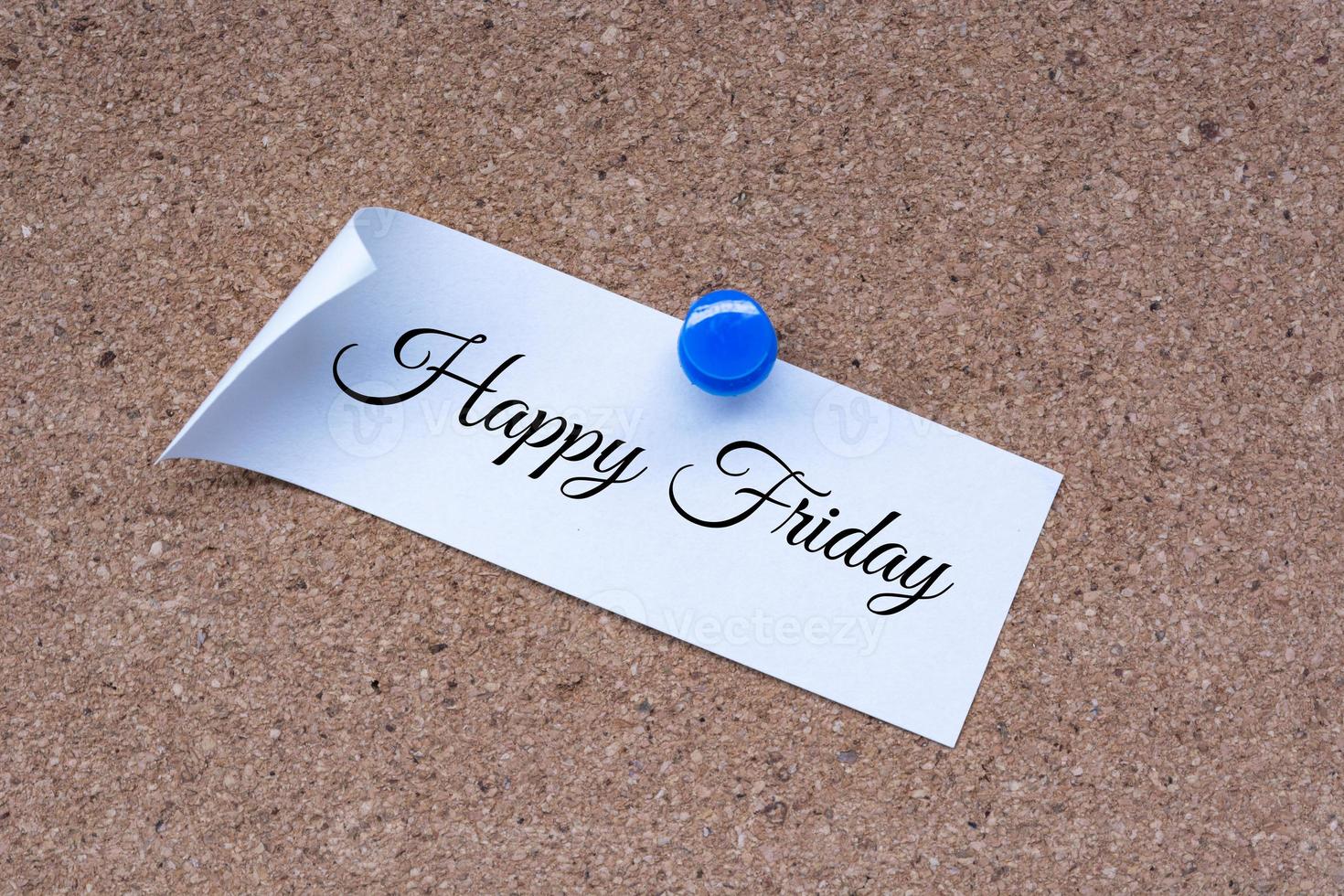 Happy Friday text on white stick note and pinned to a cork notice board. photo