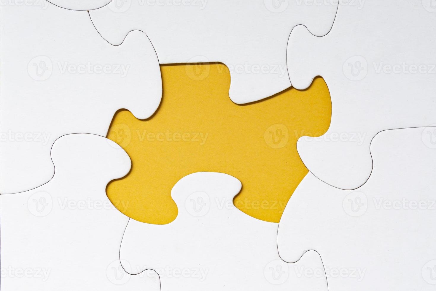 White jigsaw puzzle with some missing pieces on yellow background. photo