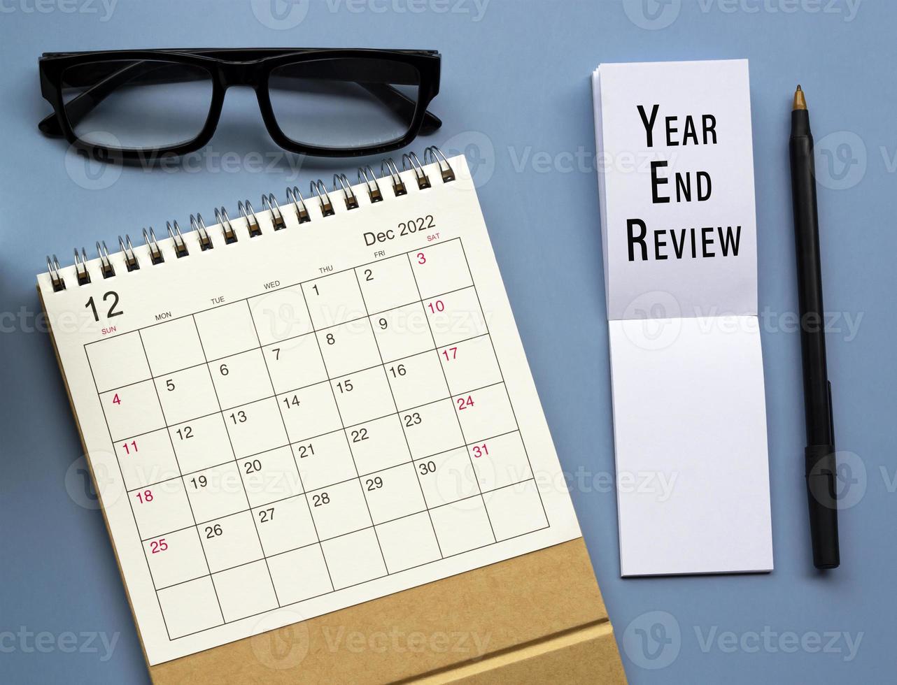 December 2022 desk calendar with Year End Review text written on notepad. photo