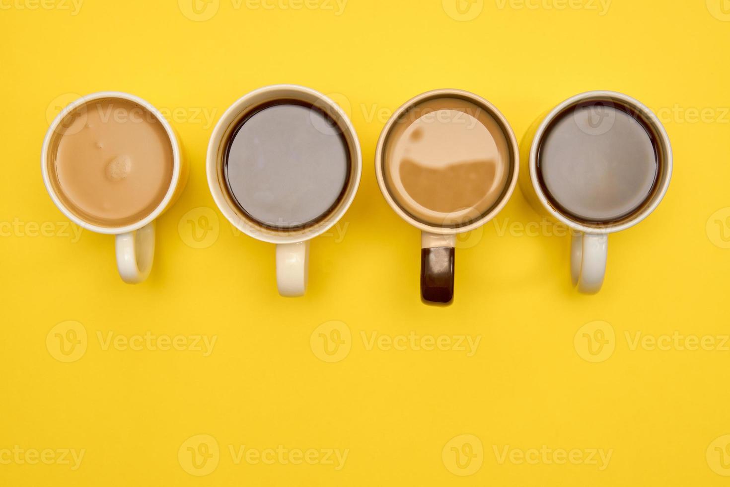 Cups of coffe - black and with milk - on yellow background. Creative concept of hot drinks. Top view, copy space photo