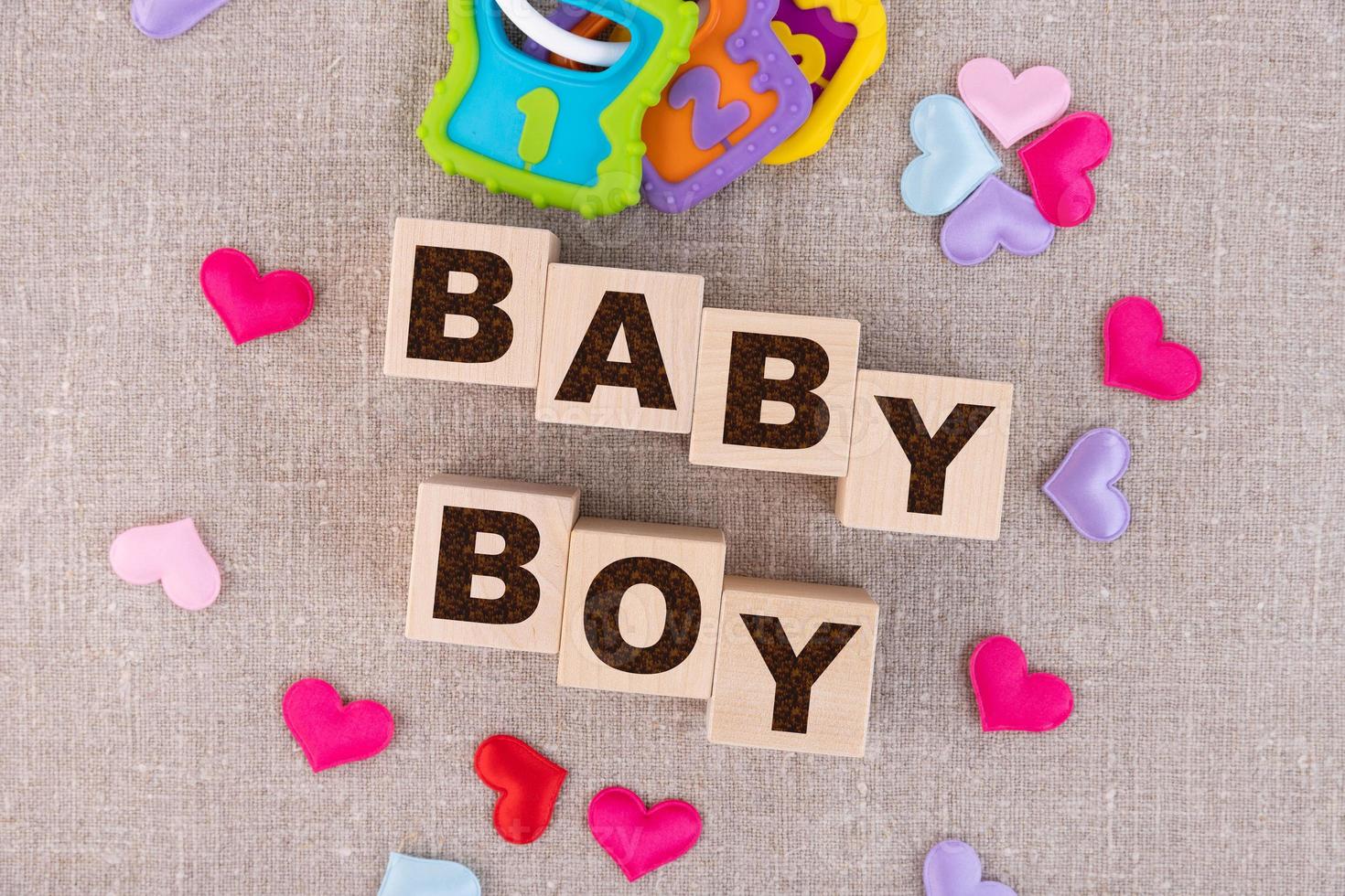 Wooden blocks with the word Baby Boy and small colorful hearts underneath. View from above photo