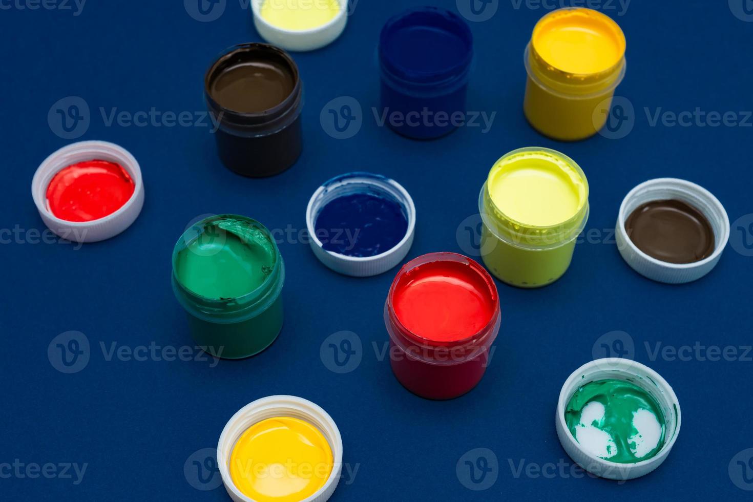 Close up of open acrylic paint cans. Colorful paints on blue background photo