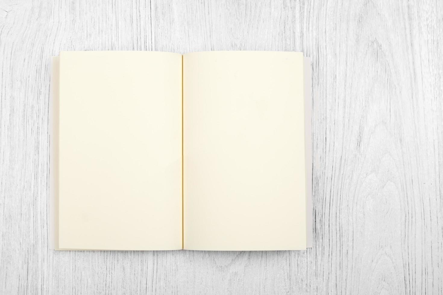 Open brown notebook and a pencil on white wooden table, top view photo