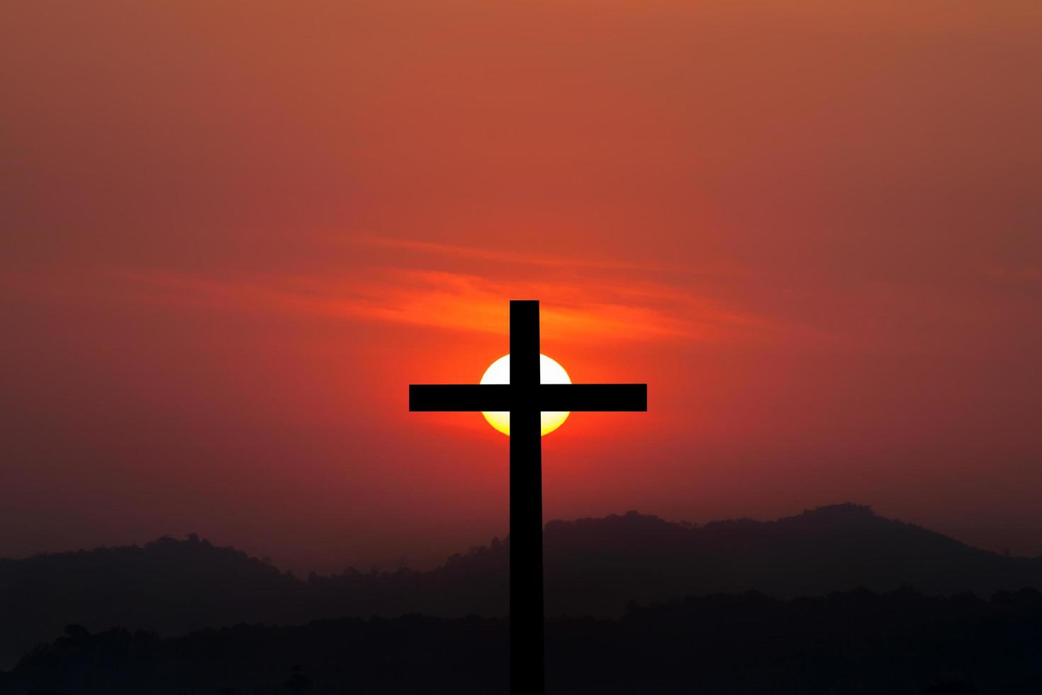 silueta de cruz sobre fondo de puesta de sol foto