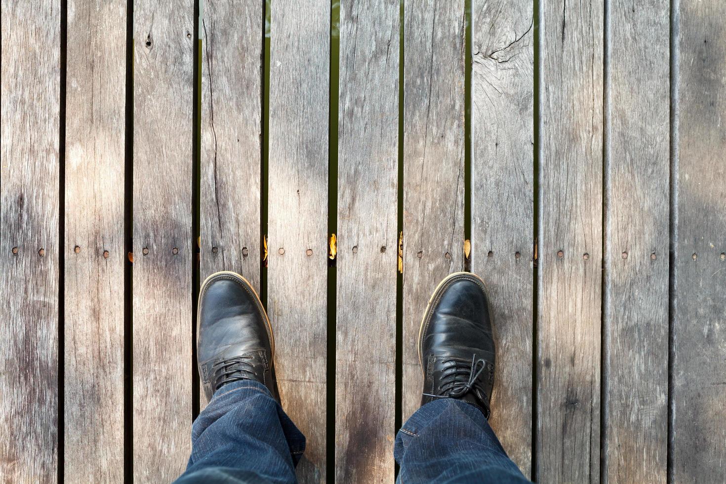 two legs wearing moccasins  and denim jeans on wooden background photo