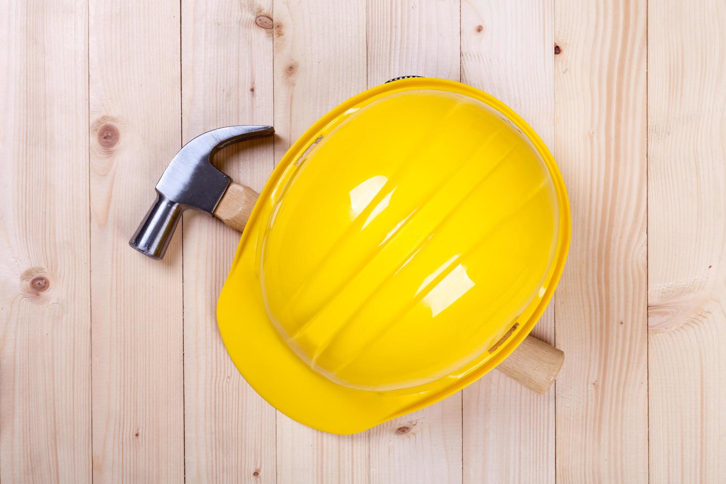 hammer and yellow hardhat on wood background photo