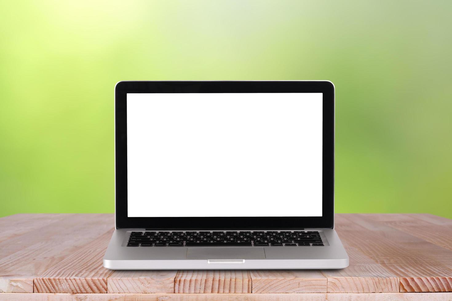 Front view of the laptop is on the work table with bokeh green background photo