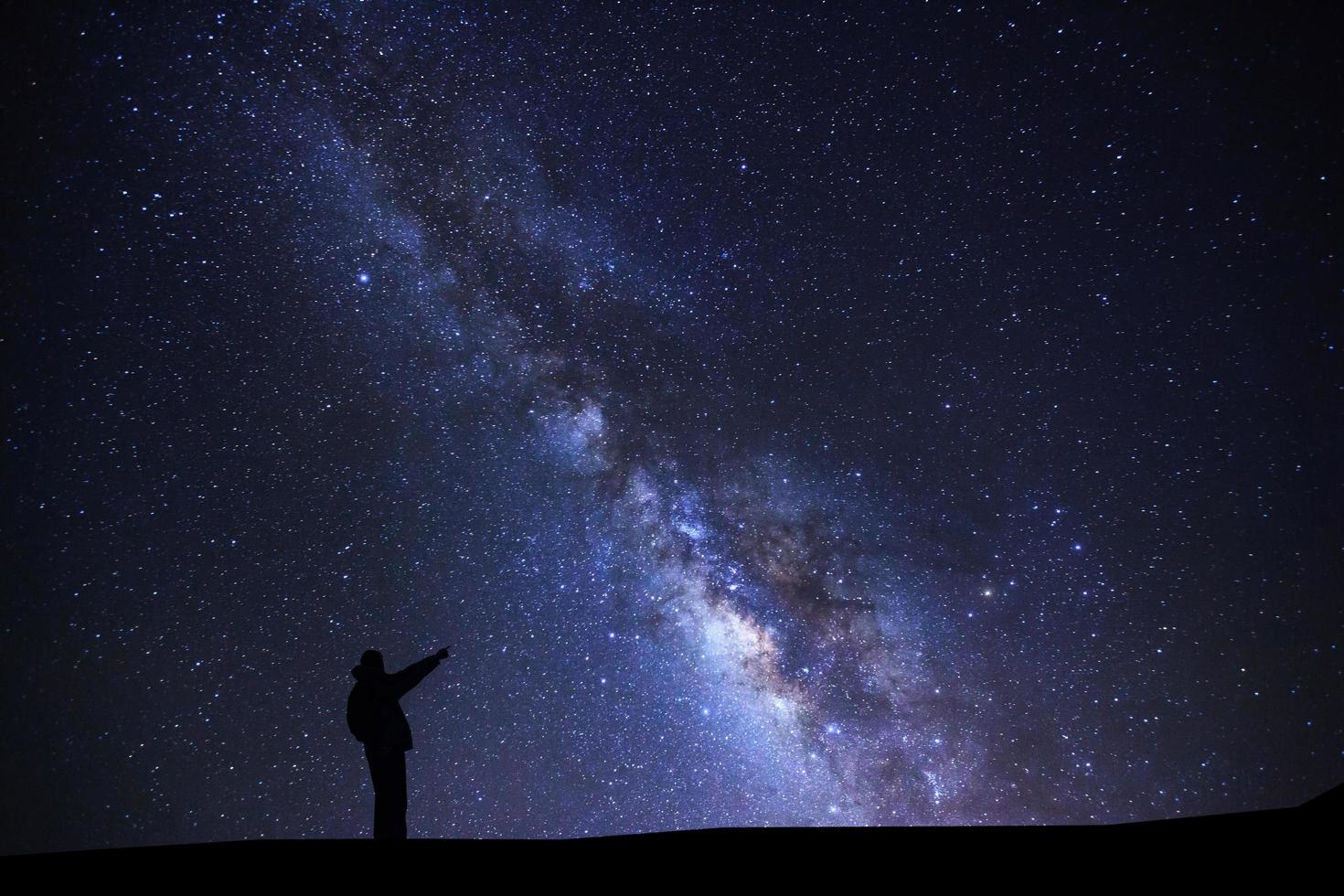 A Man is standing pointing on a bright star with milky way galaxy and space dust in the universe photo